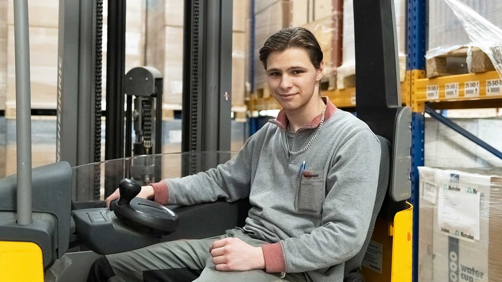 Zufriedener Ruckstuhl-Lagermitarbeiter sitzt auf Gabelstapler.
